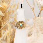 Front view of Divine Eye gold ring with turquoise center on white candle – mystical Judaica jewelry by Sages & Souls