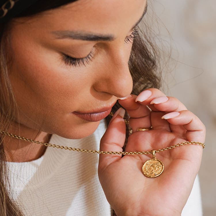 Model holding a gold pendant necklace by Sages & Souls