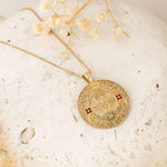 שאה pendant resting on cream plate with florals