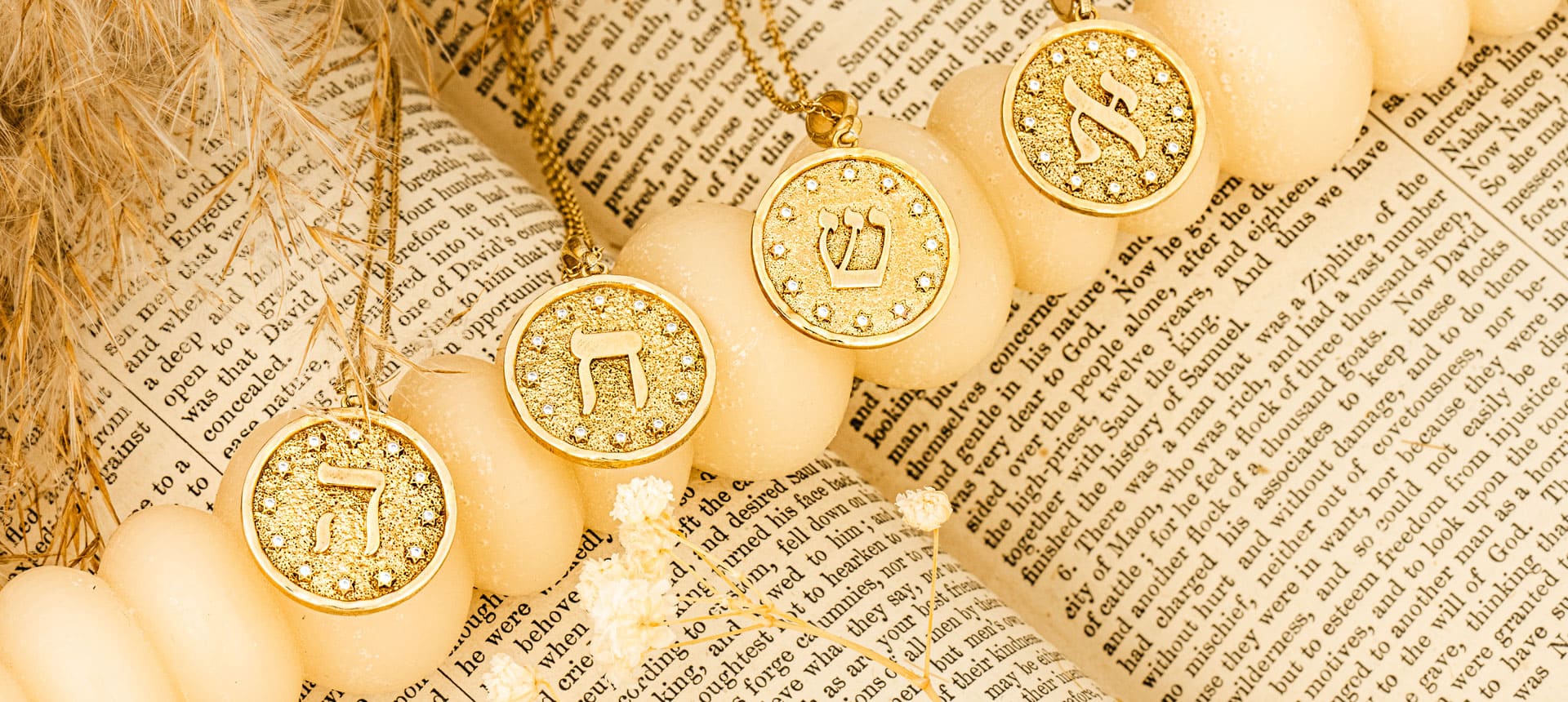 Gold necklaces with ancient Hebrew letters from the Letters of Light collection by Sages & Souls, placed on vintage Hebrew paper