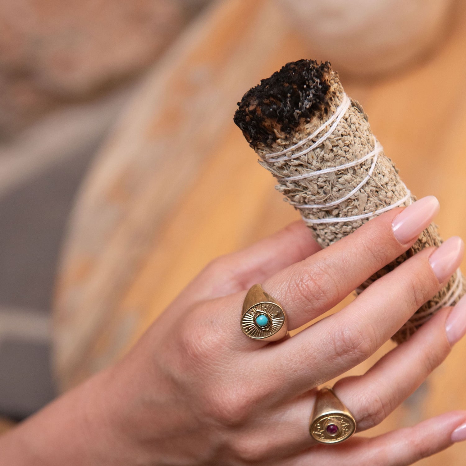 Model hand with Divine Eye Ring holding incense bundle in meditative moment
