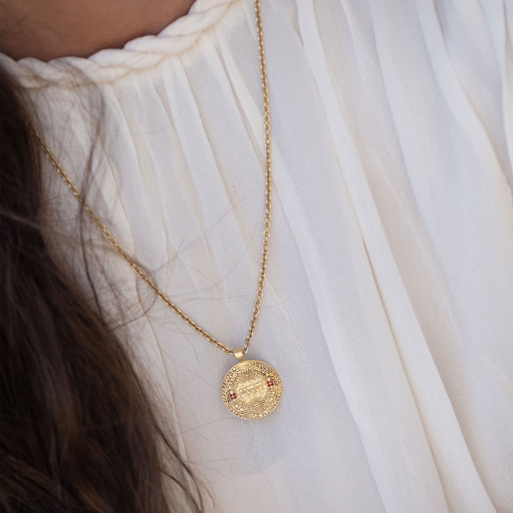ה ה ע pendant on dual chain against linen backdrop