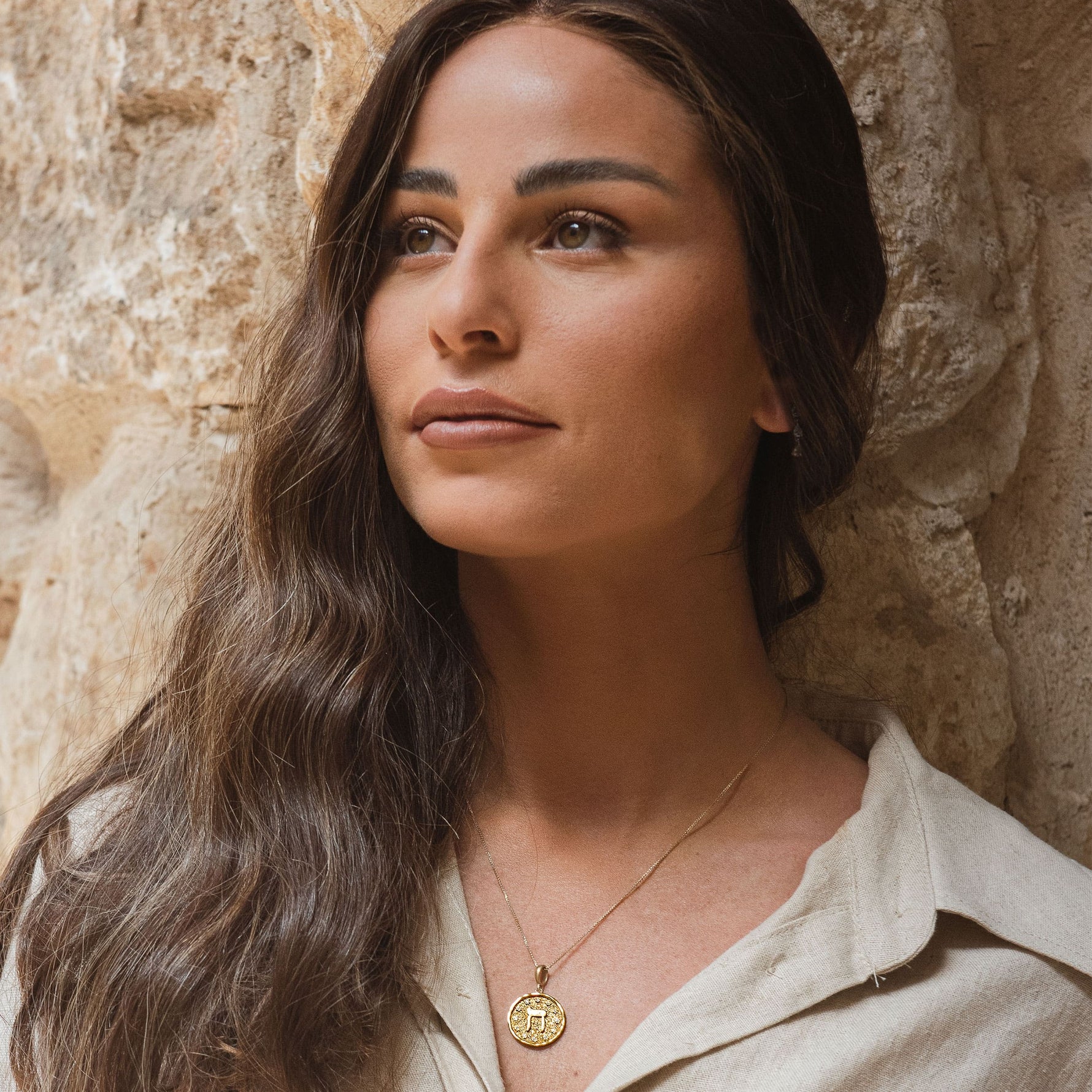 Model wearing Chet pendant against rustic stone wall