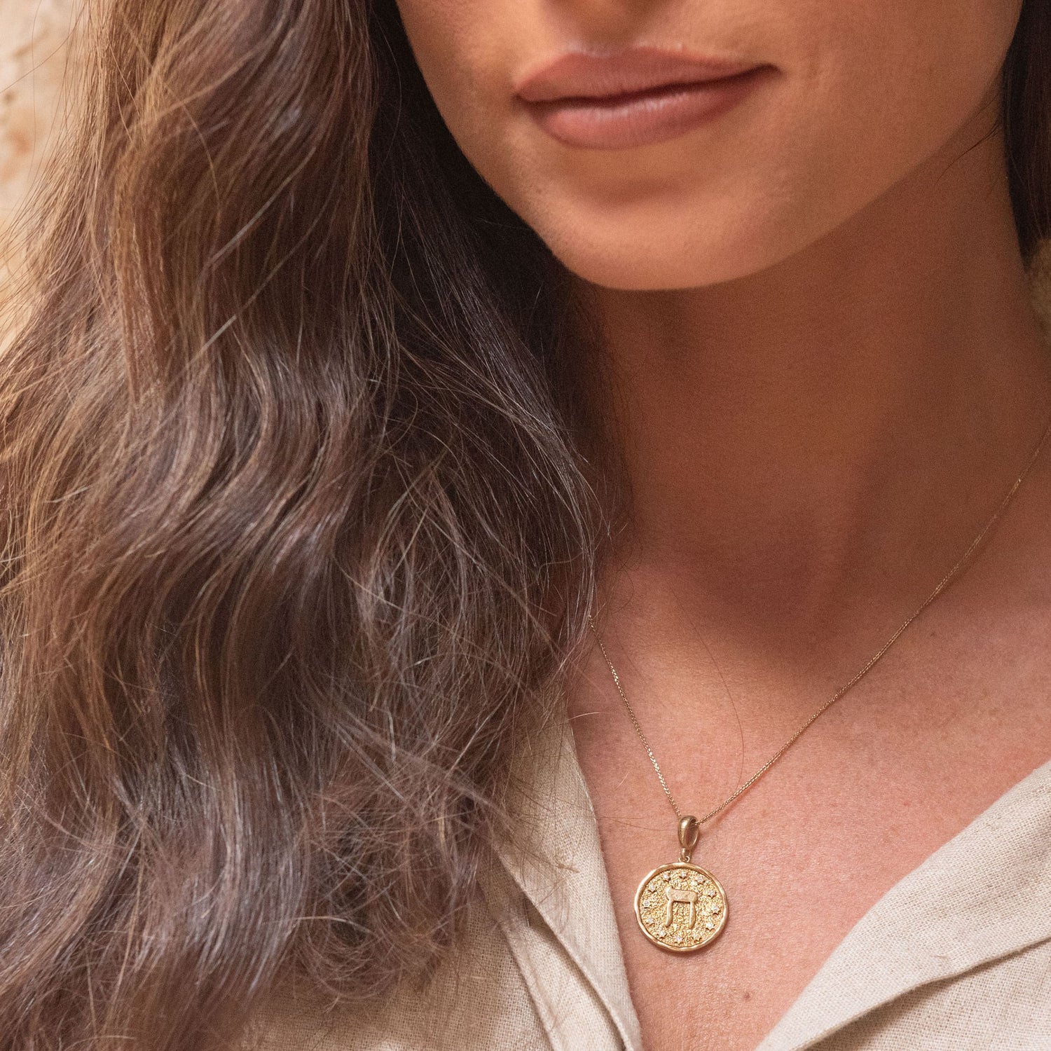 Portrait of model wearing Chet pendant gold jewelry