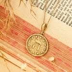 Hey pendant resting on vintage scroll warm red tones