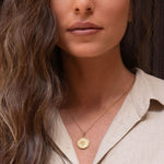 Model wearing Shin pendant over open-collar blouse