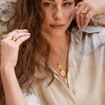 Shin pendant styled on model against stone wall 