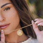 Model pinching מהש pendant between fingers warm light