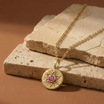 Radiant Star of David necklace in 18K gold vermeil with a pink sapphire, styled on natural stone slabs.