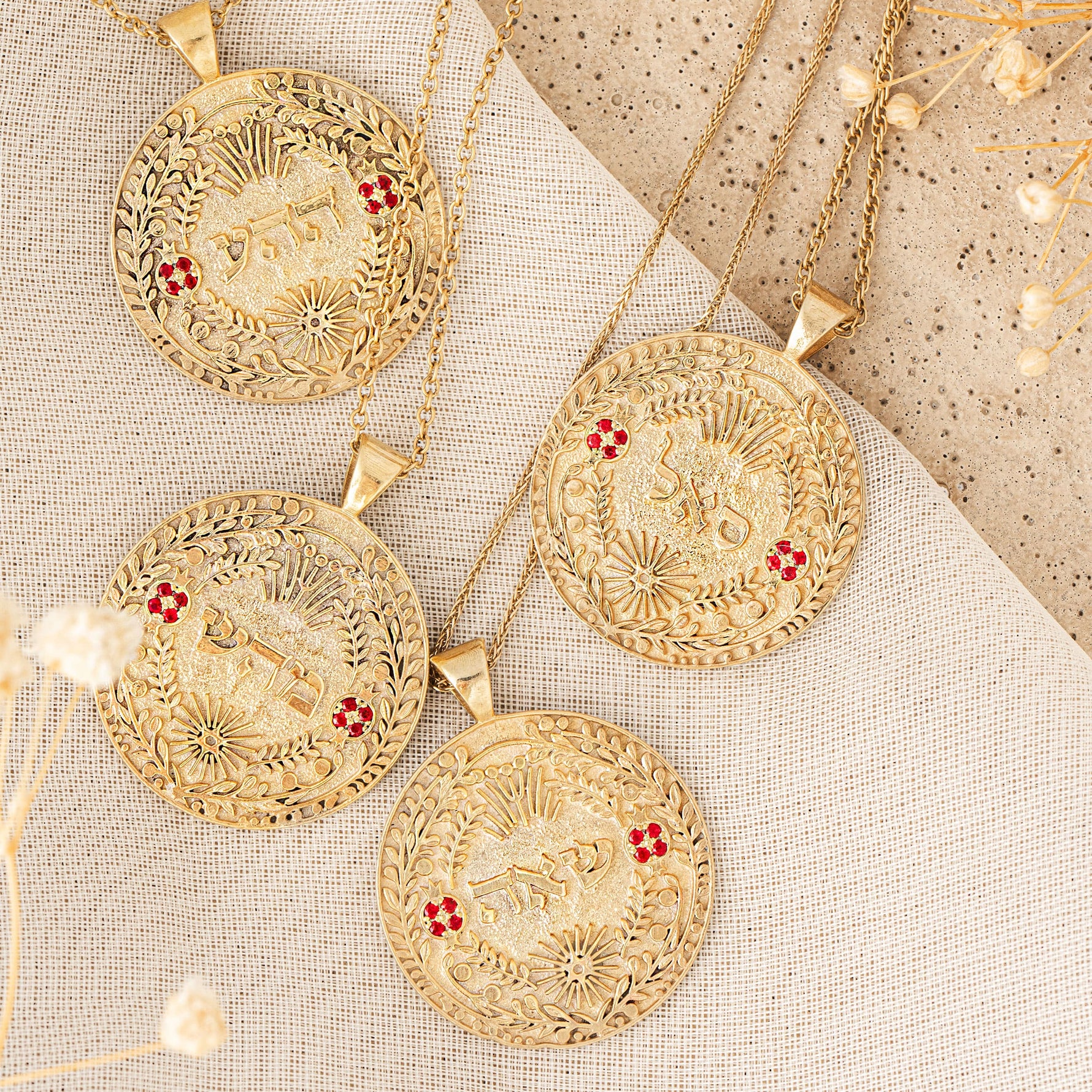 Three סאל pendants with rubies on linen flat lay