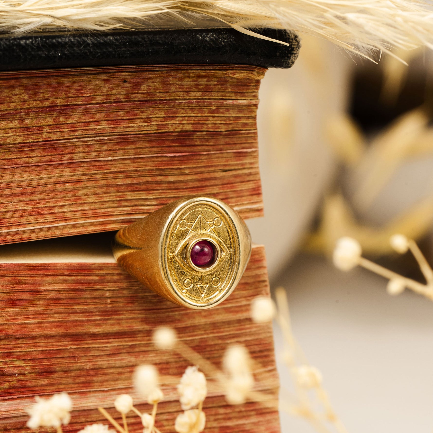 Ruby Wisdom Ring resting on book with wheat, evoking ancient study