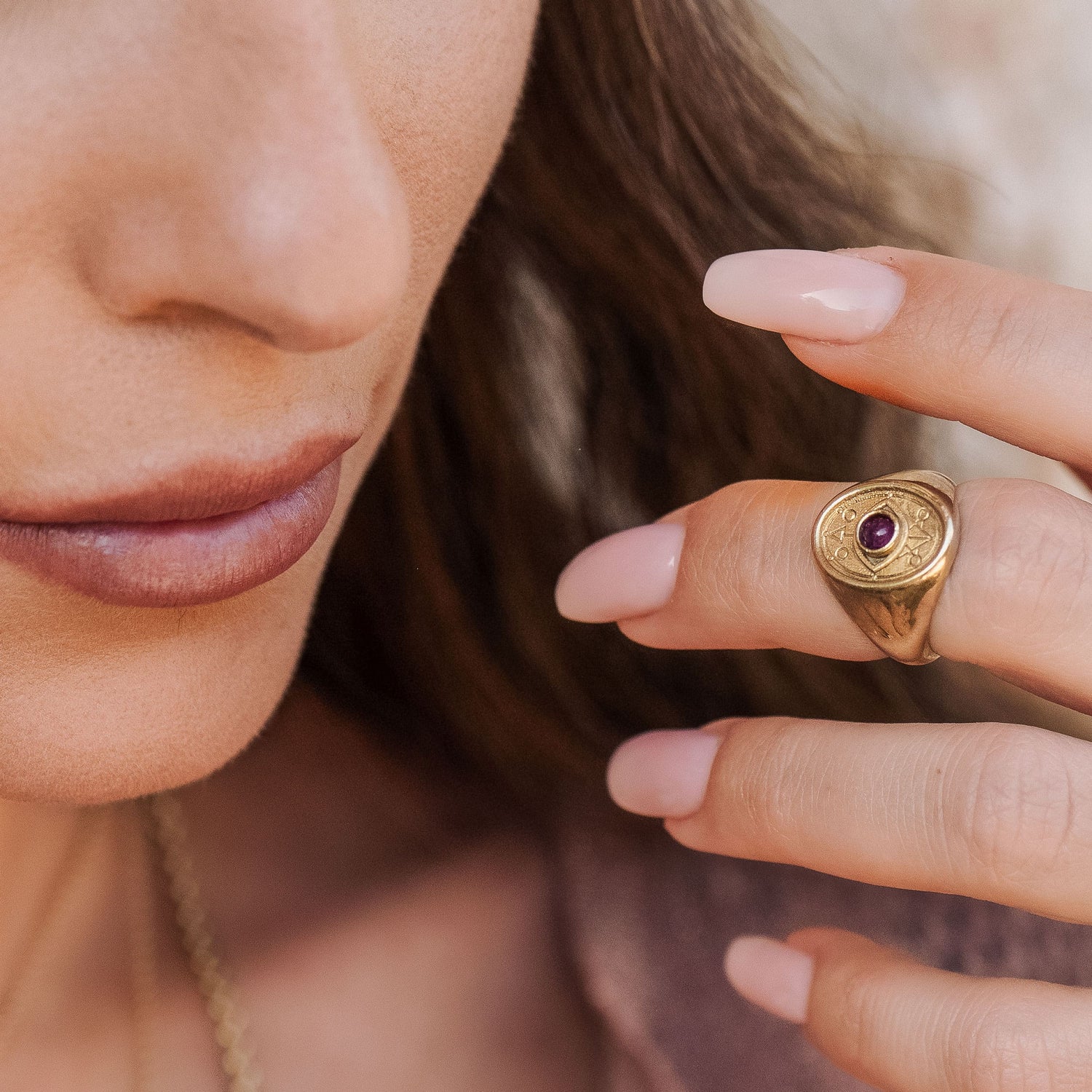 Ruby-set Wisdom Ring styled on model’s hand with soft-focus background
